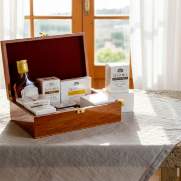 Chios Mastiha Wellness Gift Box in Mediterranean Home Setting Elenianna luxury Chios mastiha gift box with liqueur and supplements, presented on a linen tablecloth in a sunlit Mediterranean home, highlighting natural wellness.