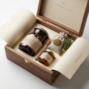 Close-up of expert hands holding freshly harvested Kalamata variety olives in a traditional wooden crate within a sun-drenched Greek olive grove.