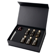 Open elenianna olive oil tasting kit showing six numbered sample bottles, a red tasting glass, and a tasting guide in a foam insert