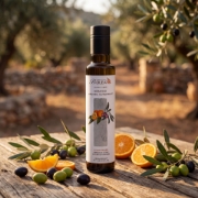 Biolea Nerantzi Organic Olive Oil bottle on a wooden table in a Cretan olive grove surrounded by fresh olives and bitter orange slices.
