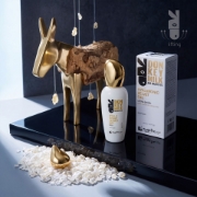 Mastic Spa Hyaluronic Velvet Eye Gel bottle and box displayed next to a decorative golden donkey statue and raw mastic tears on a sleek black glossy surface.